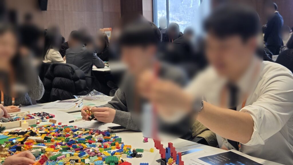 신입사원이 레고 브릭으로 타워 모델을 쌓아 올리는 비전 워크샵 장면